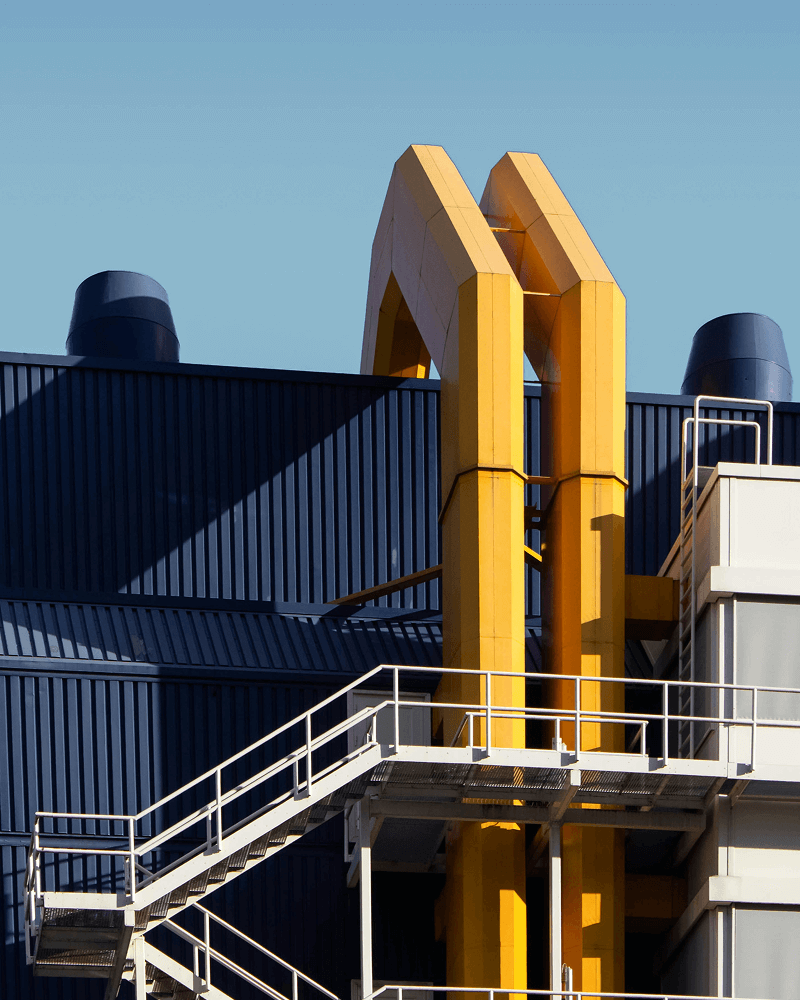 Structure industrielle moderne avec conduits jaunes et passerelles métalliques sur façade bleue.